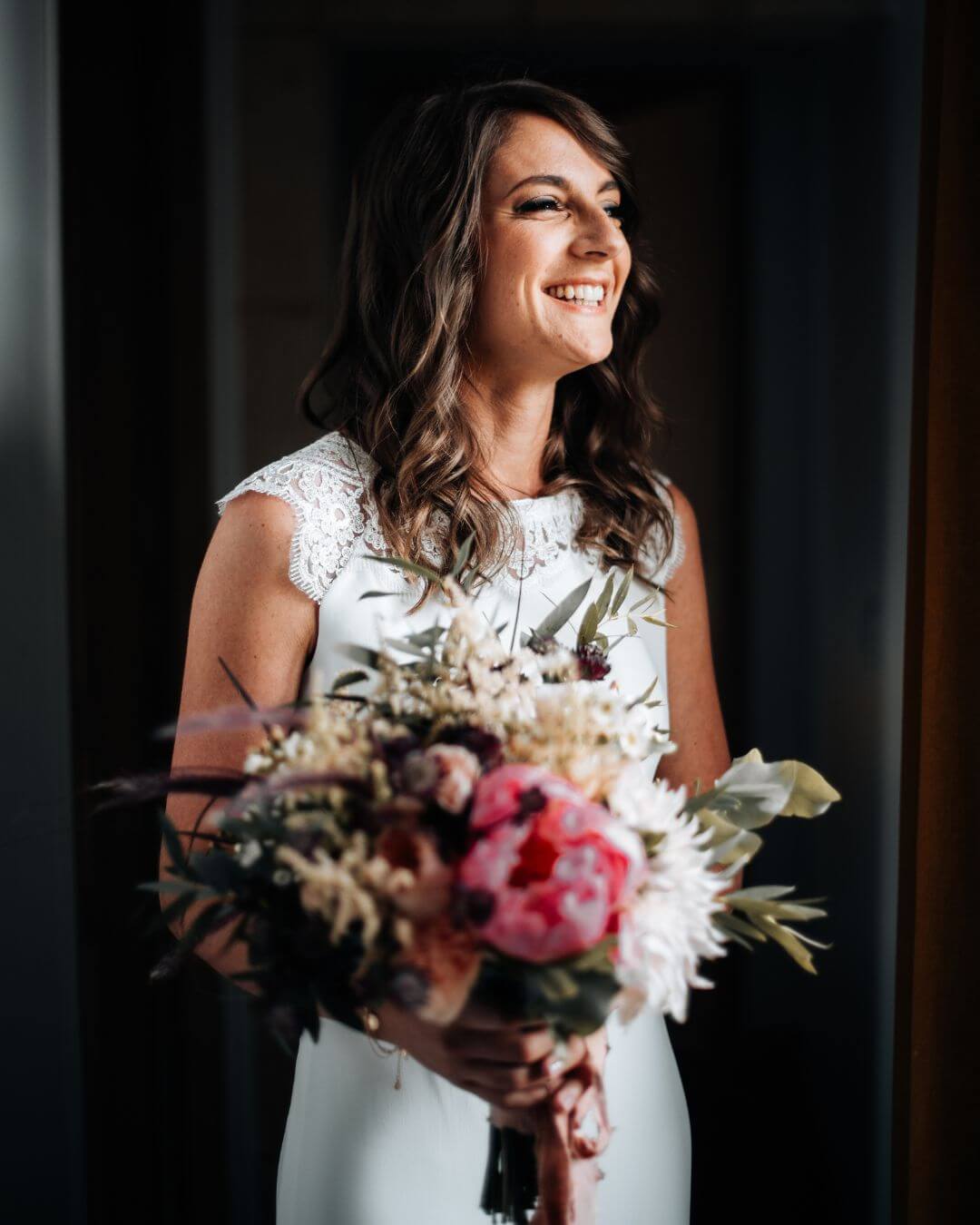 Mariée avec le sourire tenant bouquet de fleurs 